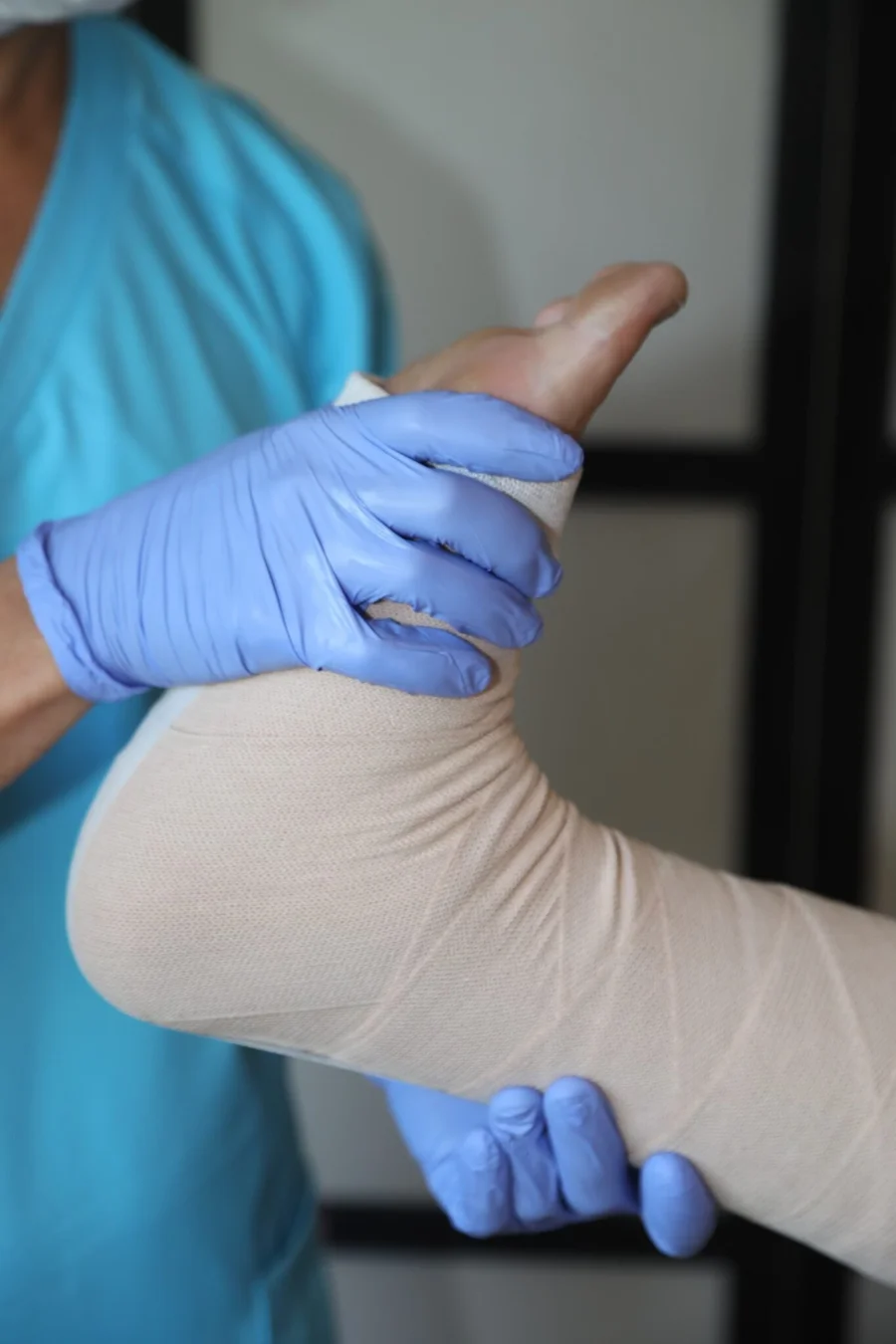 Kompressionsversorgung nach Lymphdrainage – stabilisierend und abschwellend Anlegen einer Kompressionsbandage am Unterschenkel nach manueller Lymphdrainage durch eine Fachkraft mit Handschuhen.