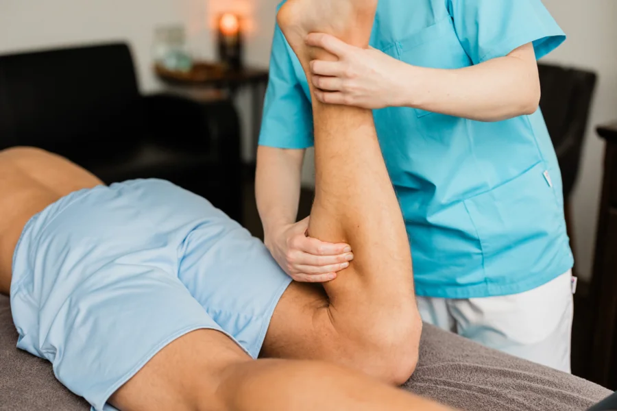 Therapeutin mobilisiert das Bein eines Patienten während einer Sportmassage