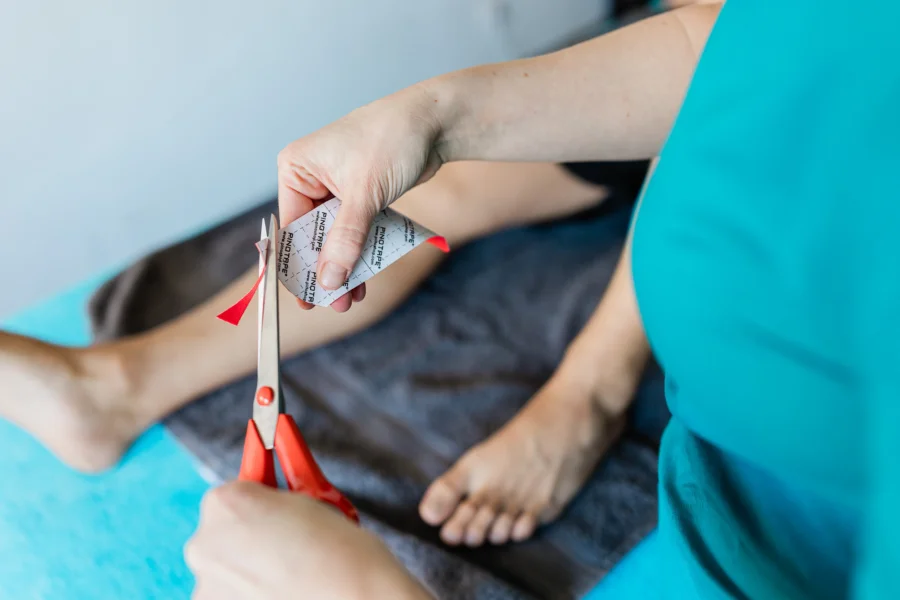 Kinesiologie-Taping Wuppertal – Katharina schneidet sorgfältig Kinesiotape zu, Vorbereitung einer Tape-Anlage in der Praxis Domo Massage Ronsdorf